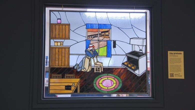 Stained glass artwork showing woman kneeling at chair praying, in an old home. 