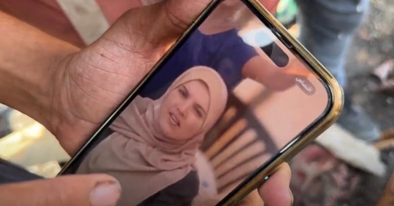 A man holds a photo of a woman on his phone.