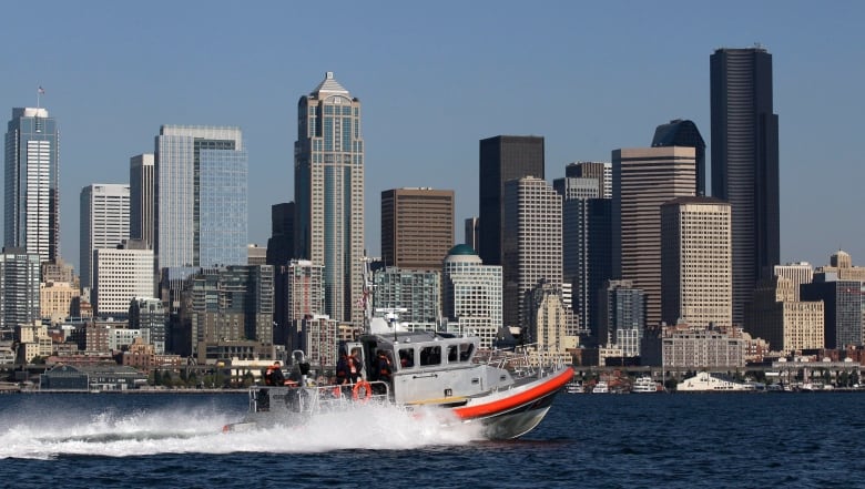 A city's skyline, with a boat flying past in the foreground.