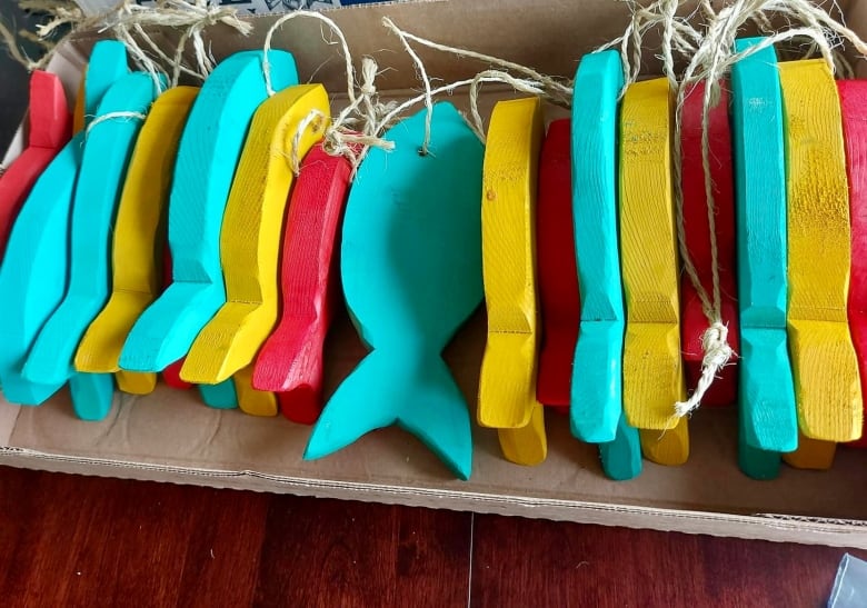 More than a dozen wooden fish, painted different colours, are neatly lined up in a box.