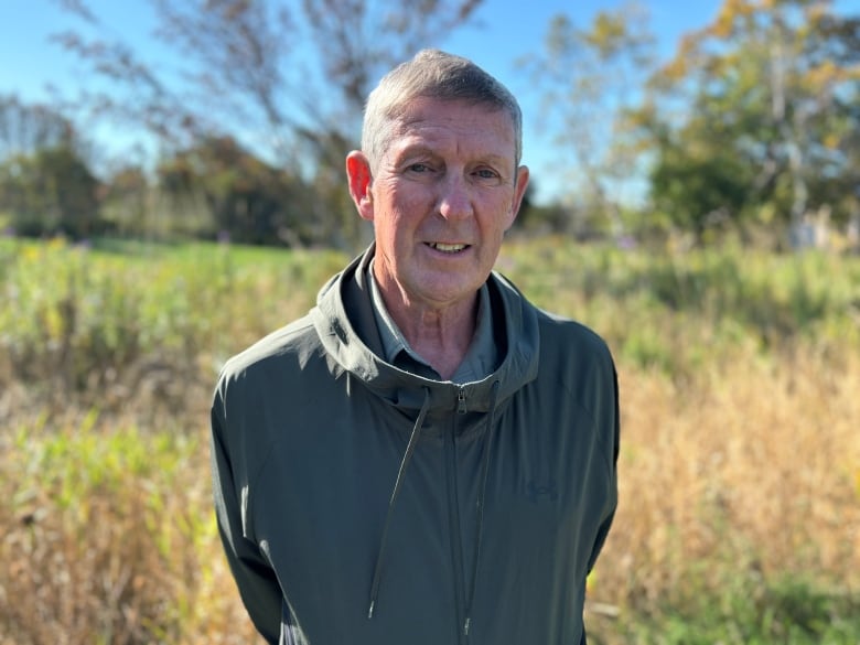 A man stands in front of a field.