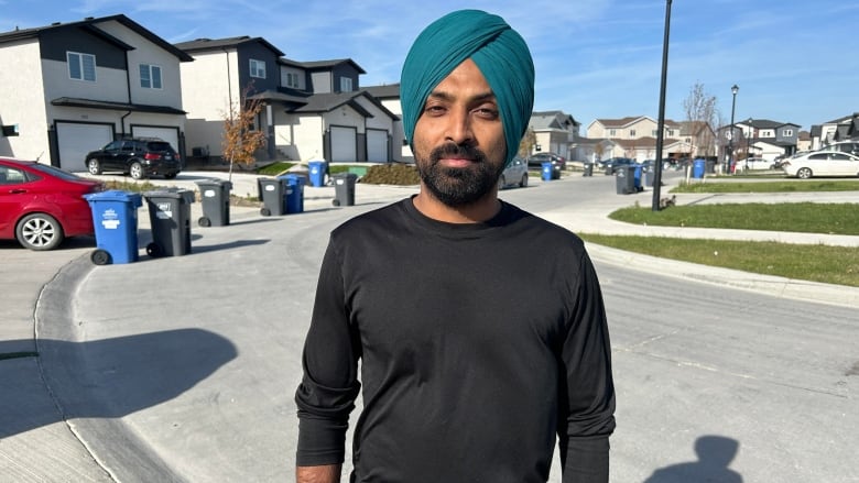 A man wearing a turban is pictured standing on a residential street.