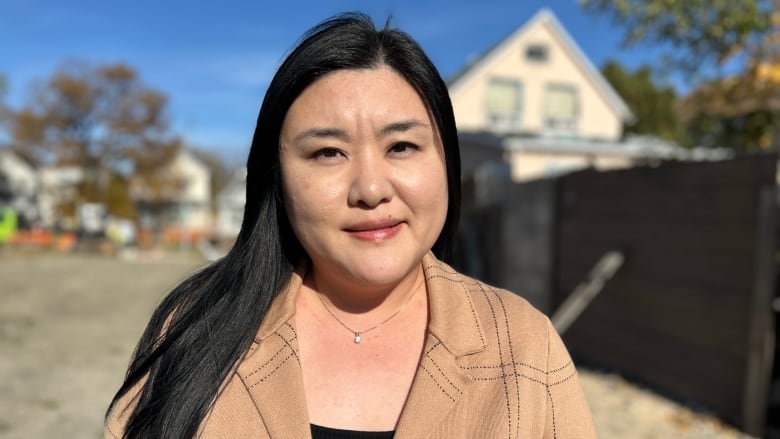 An Asian woman is standing in a vacant lot.