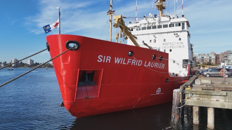 A red vessel docked in Victoria with a blue sea in the background.