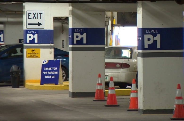 The inside of an underground parkade, showing parked cars and support posts.