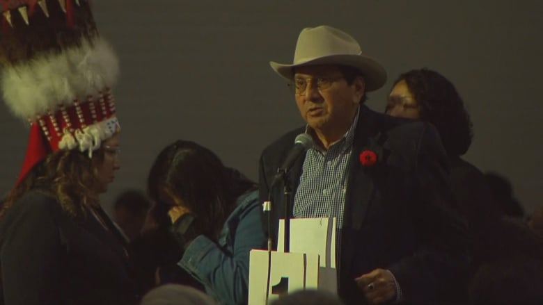 Chief Roy Fox stands at a microphone holding a piece of paper aloft.