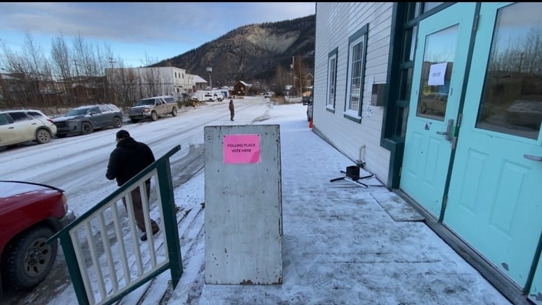 A sign on a snowy sidewalk.