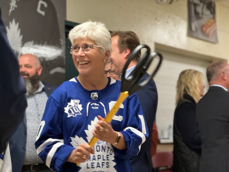 A woman holds a large pair of scissors