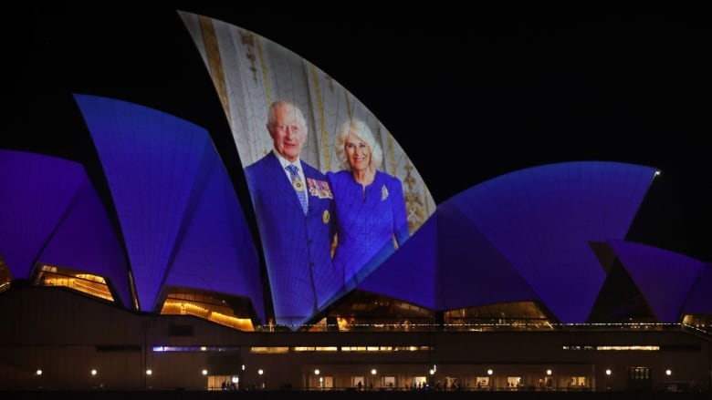 A picture of two people is projected on the roof of the Sydney Opera House.