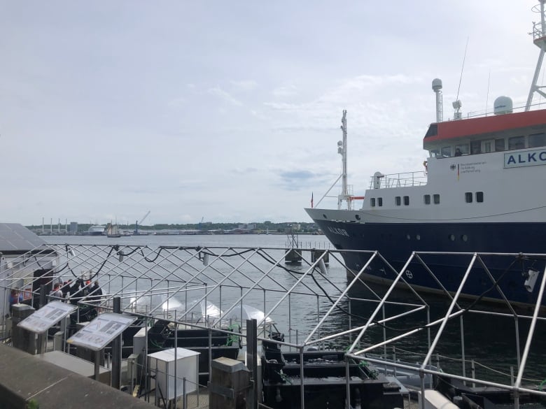 A view from a harbour, a big boat is in the background, and in the foreground several clear plastic bubble structures can be seen on the water.