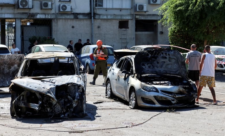 People stand around heavily damaged cars.