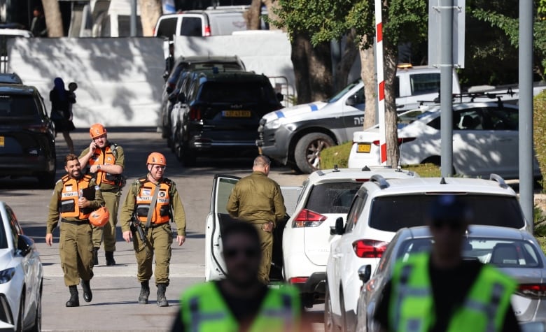 Security personnel walk down a street that has been cordoned off by authorities.