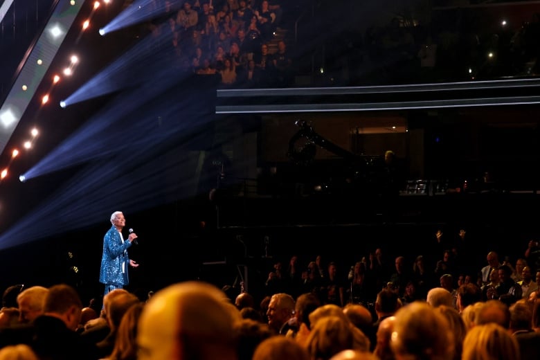 A singer performs onstage as an audience watches.