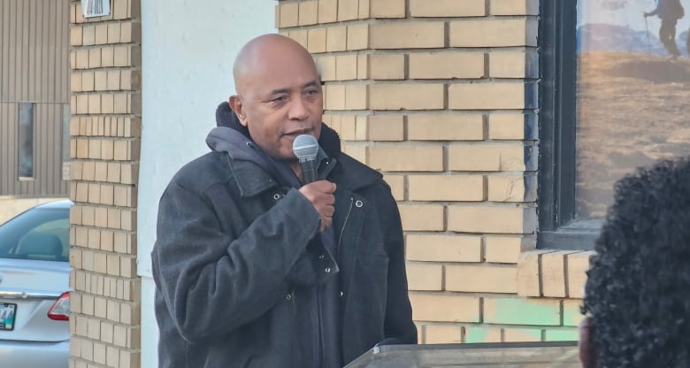 A man holding a mic from behind a podium.