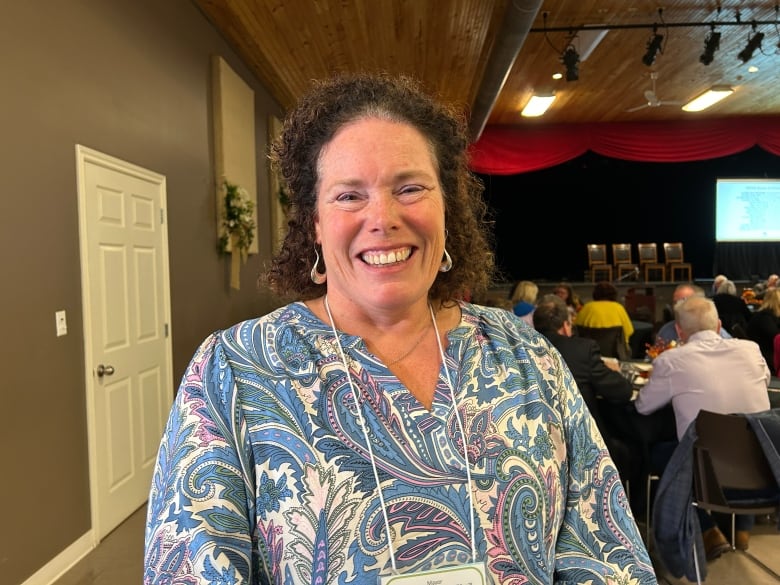 Woman with blue patterned top smiling.