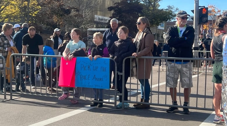 People standing behind metal fence.