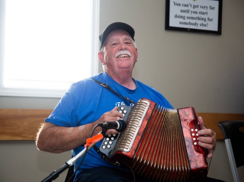 A man in a blue shirt playing an accordion. 