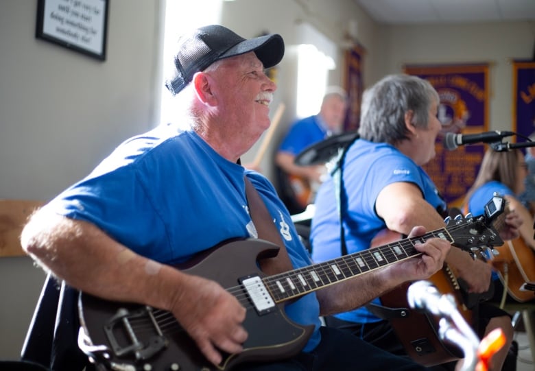 A man in a blue shirt playing a guitar. 