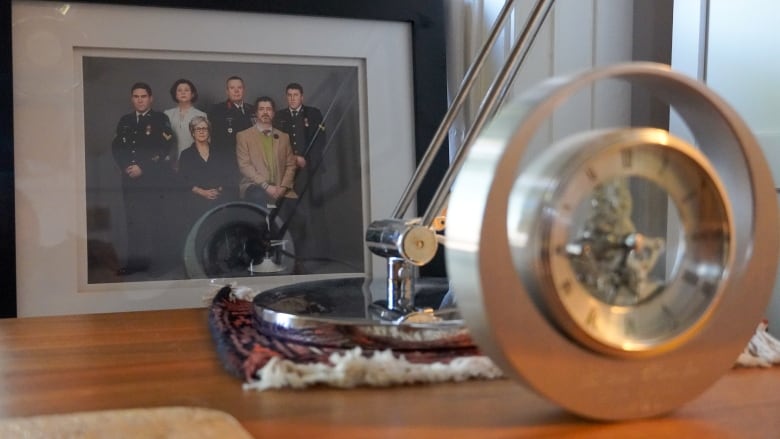 A framed photo of a group of six people with a desk lamp and clock in the foreground.