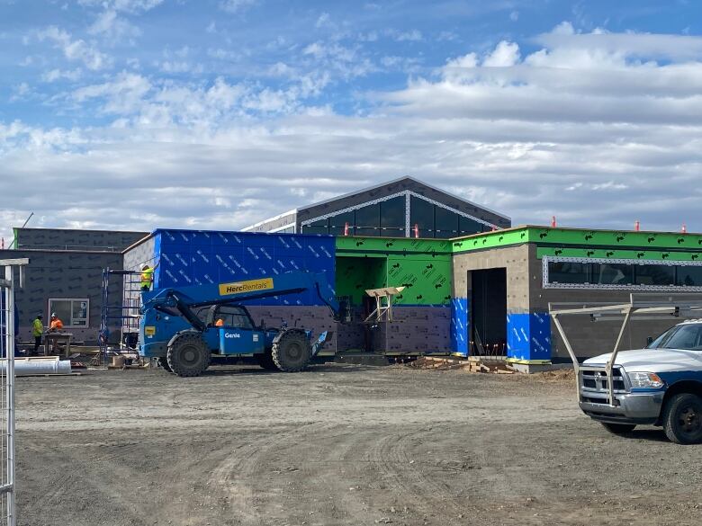 Work vehicles surround a building under construction.