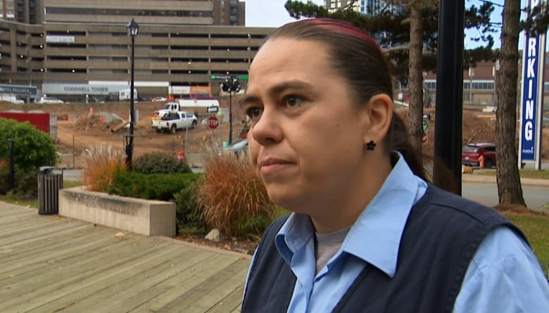 Michelle stands outside of her work next to the construction. 