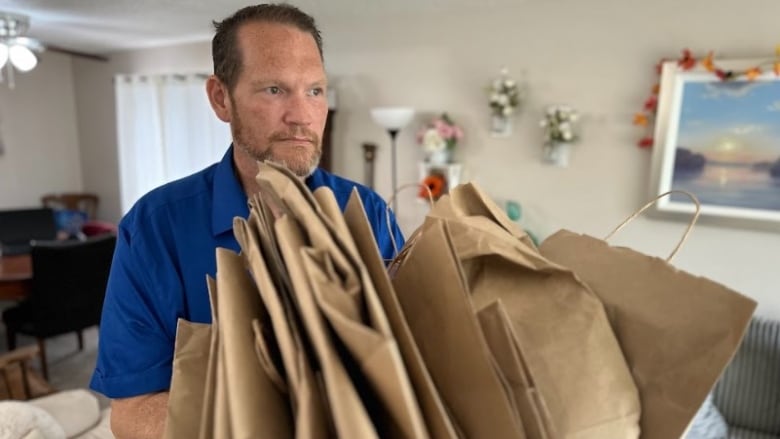 Steve Calarco holding a pile of paper bags. 