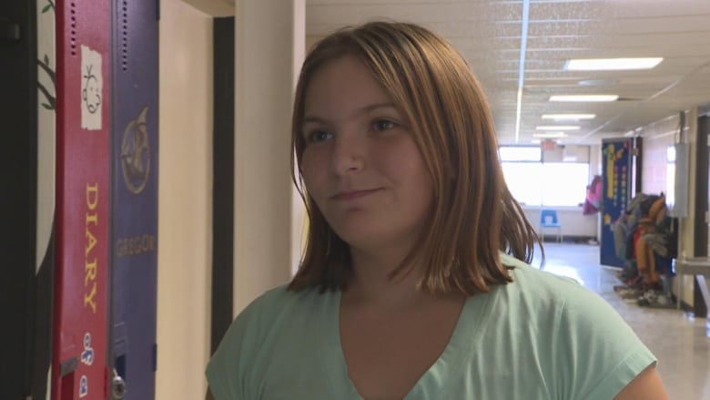 A pre-teen girl with blonde hair and a green shirt.