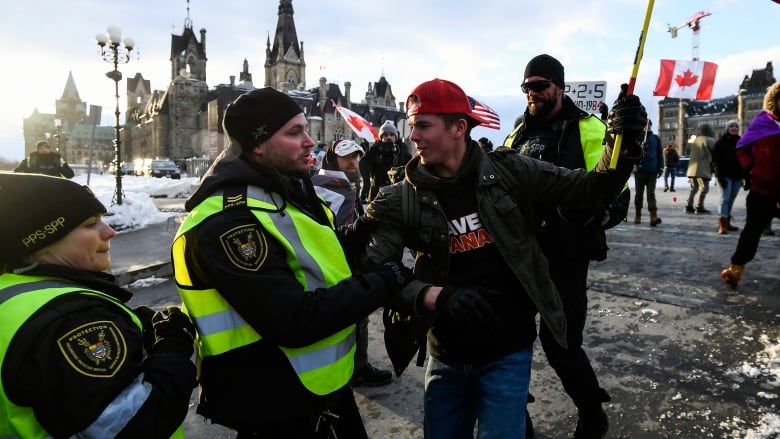 An unidentified demonstrator interacts with members of the Parliamentary Protective Service on Parliament Hill, as protesters mark the one year anniversary of the Freedom Convoy in Ottawa, on Saturday, Jan. 28, 2023.