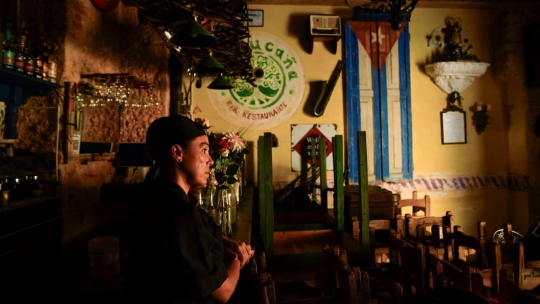 A person is pictured inside a dark restaurant during a power outage.