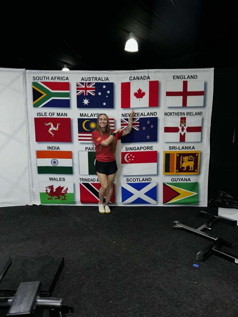 Woman wearing sports attire points at Canada flag smiling