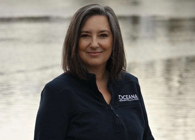 A smiling woman in front of a body of water