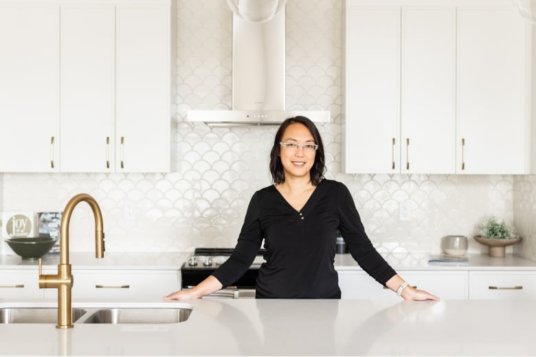 A woman stands in a bright kitchen.