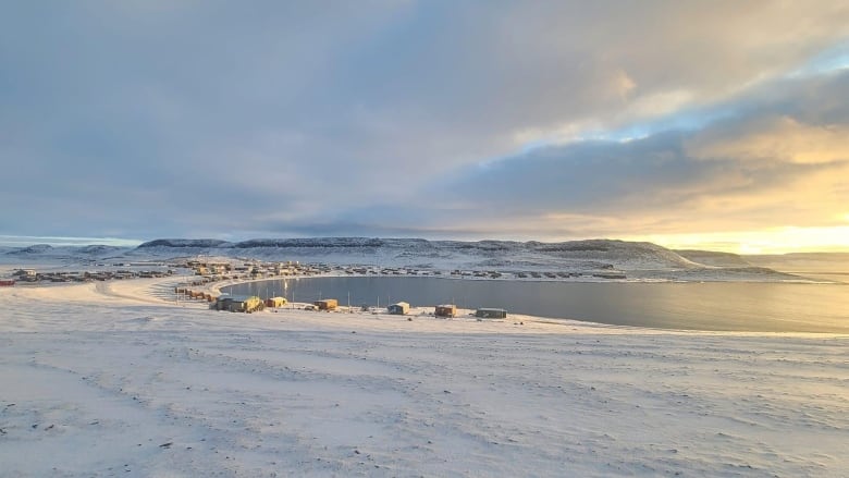 a landscape image of homes around a bay under a sunrise