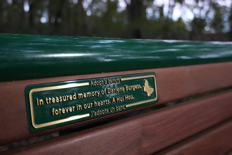 A green plaque with gold letters reads, 'In treasured memory of Darlene Burgess. Forever in our hearts. A Hui Hou.' There is a butterfly beside it. 