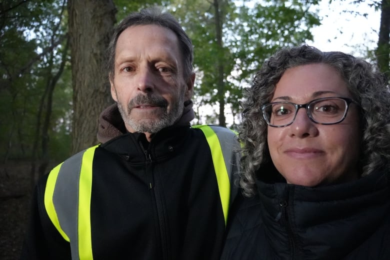 A man and a woman stand smiling at a camera.