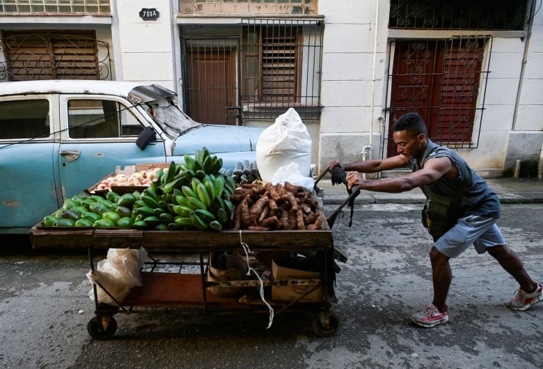 A man pushes a cart full of vegetables along a street in Havana, Cuba.