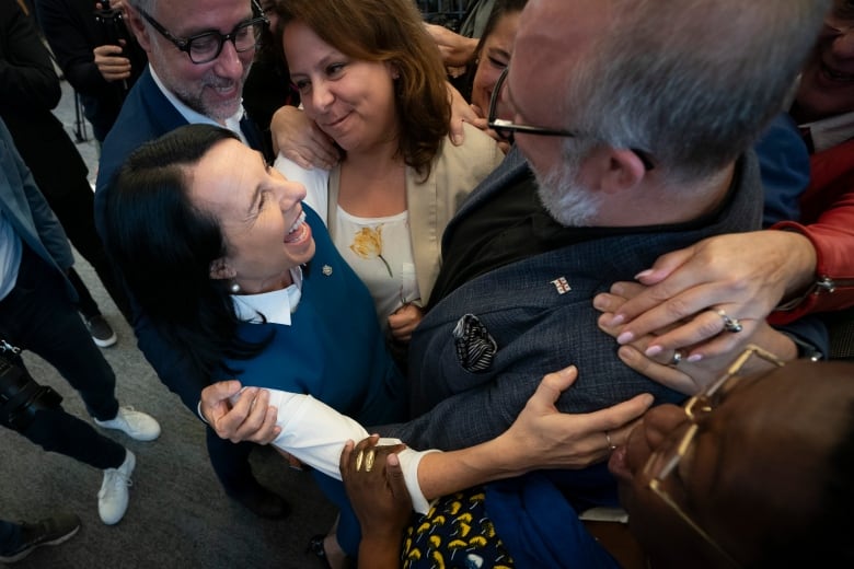 woman smiling as she hugs a group of people.