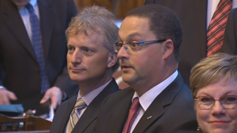 Two men and a woman sitting next to each other in formal attire