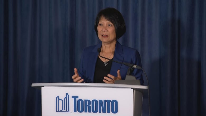 Woman in a blazer at a podium 