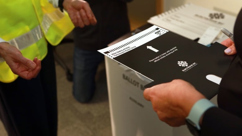 A person holds out a voting card to a poll worker.