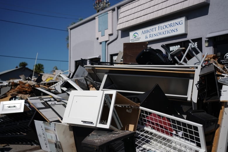 Broken furniture is piled in front of a building with the sign 'Abbott Flooring and Renovations'