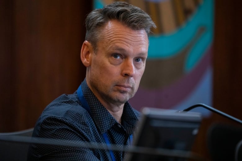 A man in a blue shirt behind a screen