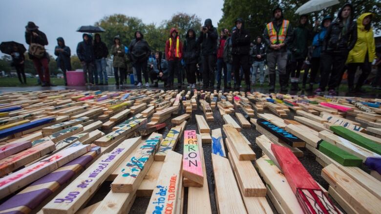 Wooden stakes, some painted with people's names, are laid out on the ground. 