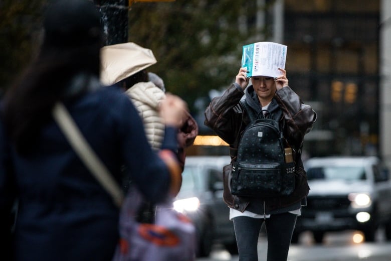 A person shades themself from the rain using a flyer