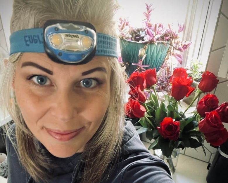 A woman smiles at the camera with a blue headlamp across her forehead. 