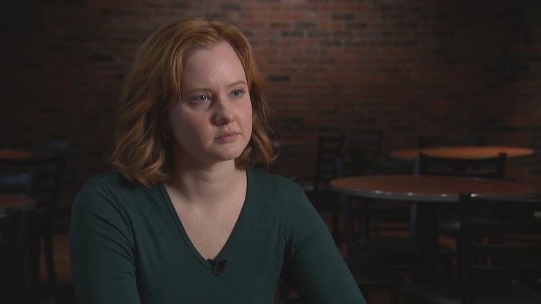 A red haired woman is sitting, wearing a green shirt