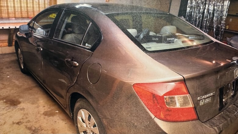 A grey or light brown Honda Civic parked in a garage. 