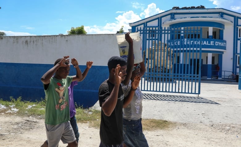 People raise their arms while walking past a police station