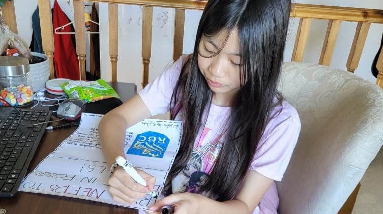 A young girl sits at a desk writing.