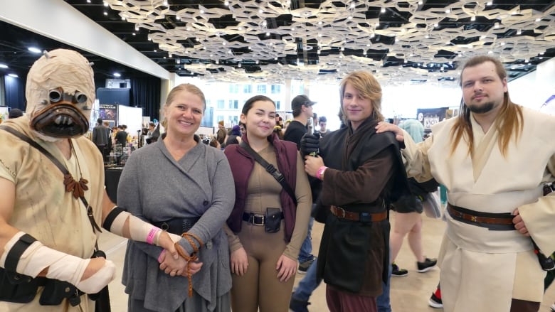 A group of people dressed in Star Wars costume attend an event. 